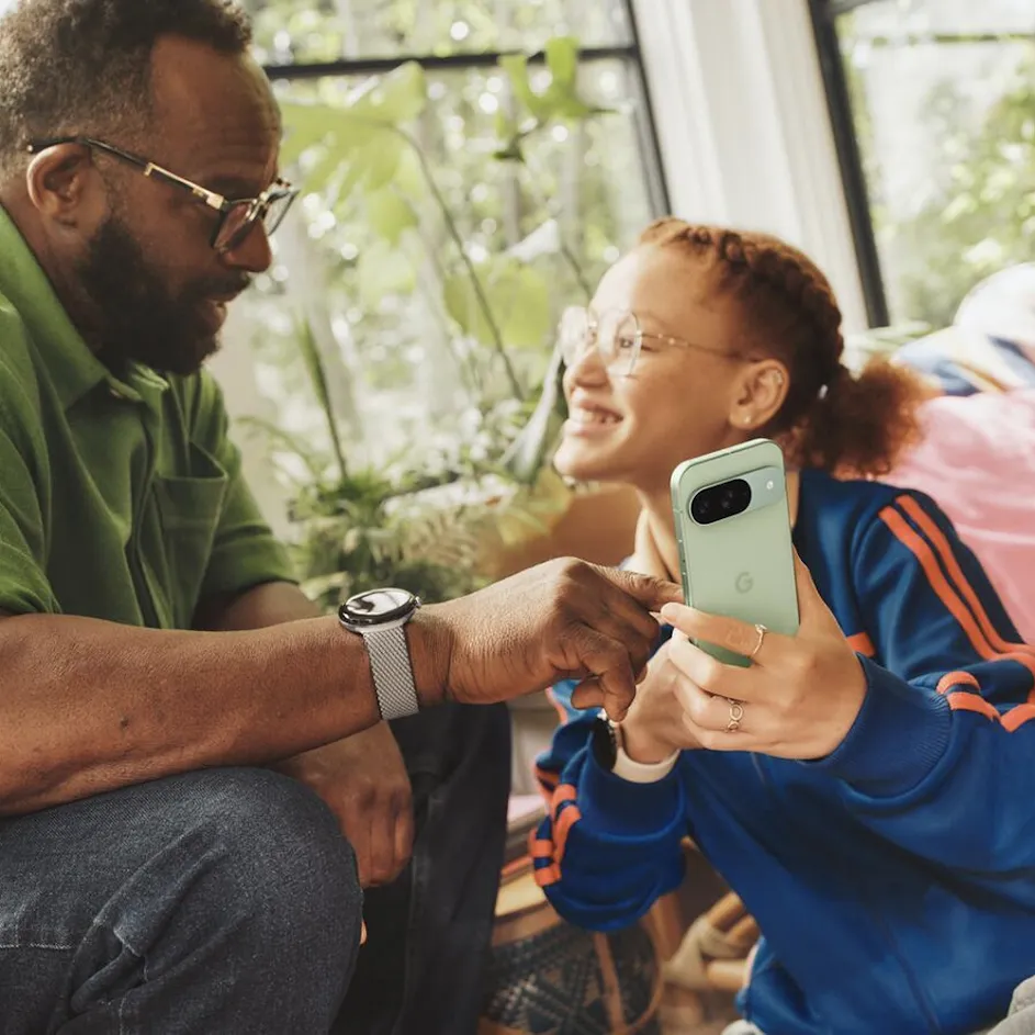 Photograph of a father and daughter sitting together inside their cozy home, surrounded by natural light and plants. The father is pointing to something on the smartphone his daughter is holding as she smiles back at him. In the upper-left corner, an icon for a child’s user profile is overlaid on the photograph.